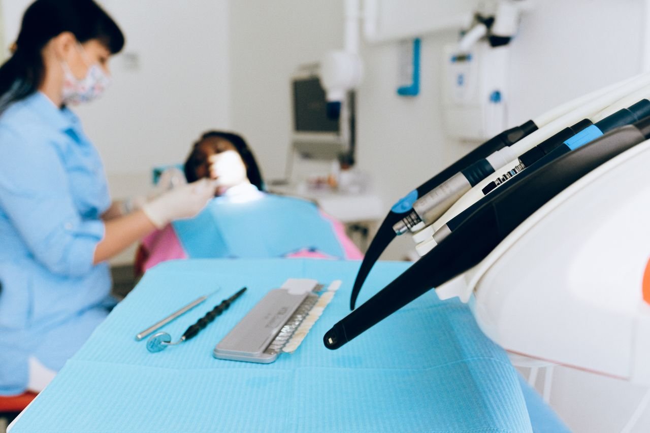 Dental check-up scene with dentist attending to patient, focus on tools.